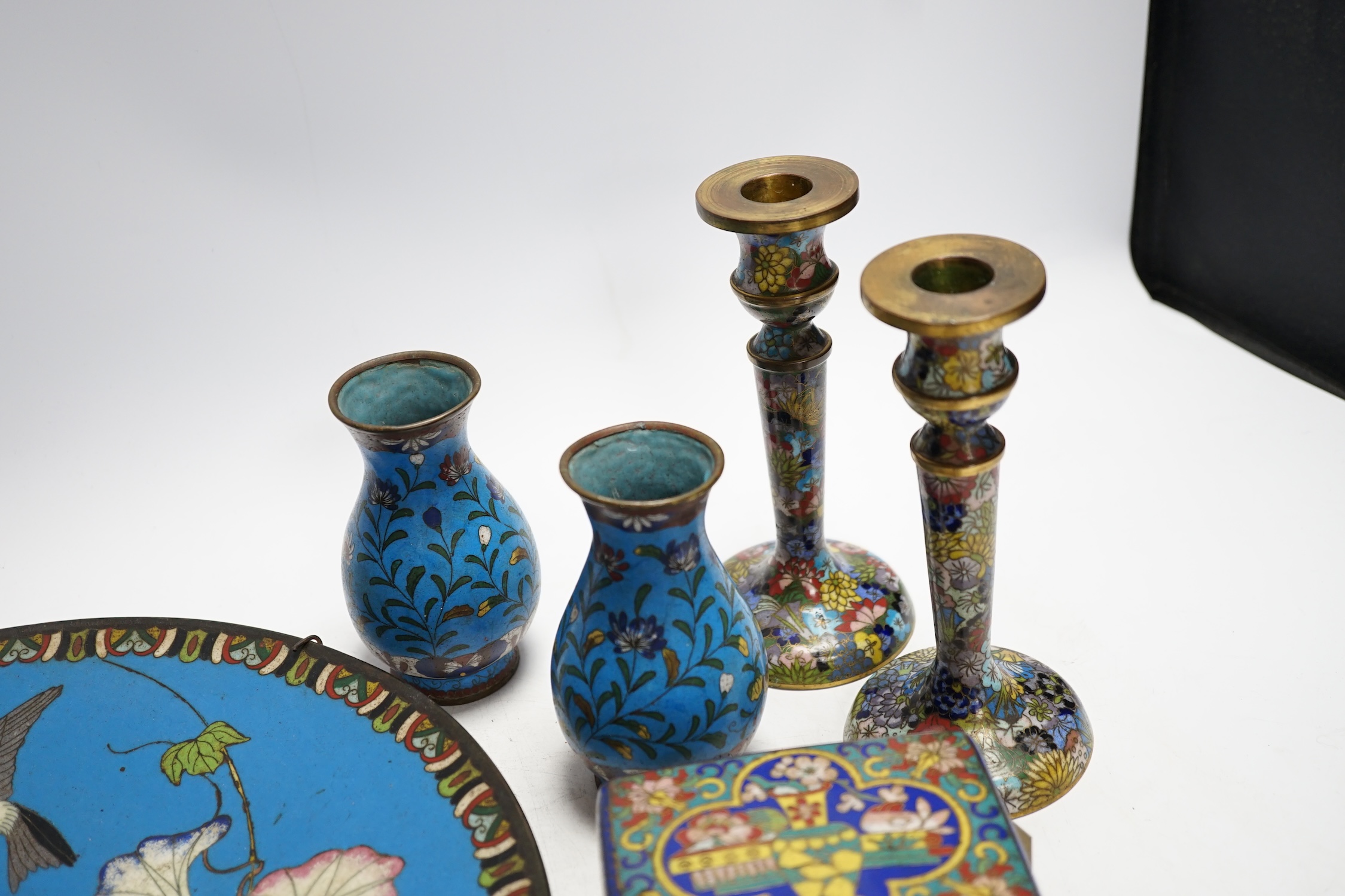 Seven Chinese or Japanese cloisonné enamel items including a pair of candlesticks, 15cm high, a charger, two boxes and a pair of vases